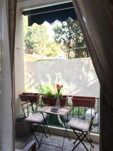 una mesa con sillas y un jarrón de flores en el balcón en 6 Keys, en Pisa