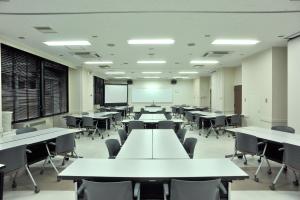 un aula vacía con mesas y sillas blancas en Refre Forum en Tokio
