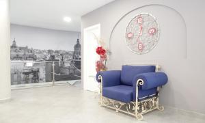 セビリアにあるItaca Artemisa by Soho Boutiqueの壁に時計が付いた客室内の青い椅子