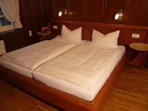 ein großes Bett mit weißer Bettwäsche und Kissen in der Unterkunft Elektro-Hotel Rosenhaus GmbH in Velbert