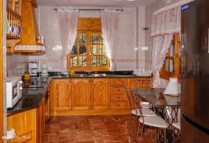 una cocina con armarios de madera y una mesa con sillas. en Villa Cristina, en Benaoján