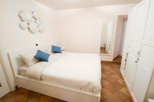a white bedroom with a white bed with blue pillows at Il balcone di Angelina in Isola del Liri