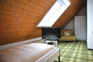 a bedroom with a bed and a tv and a window at Altbau Gasthaus Amboss in Grünkraut