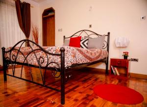 a bedroom with a bed with pillows and a red rug at Sherry Homes - Kwetu in Nairobi