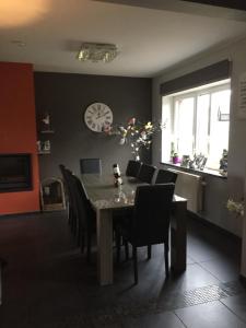 a dining room with a table and chairs and a clock at Ferme de la Petite Fagne in Spa