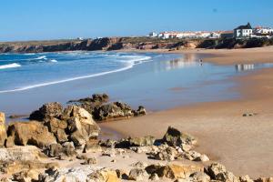 a beach with rocks and the ocean and buildings at Friendly Peniche Apartment in Peniche