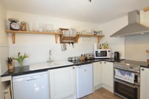 a kitchen with white cabinets and a sink and a stove at Althea House with parking in Padstow