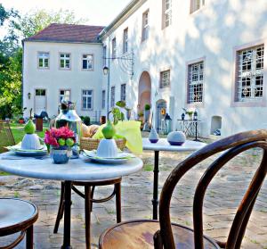 巴特弗赖恩瓦尔德Event- Kultur & B&B Kunst Schloss Neuenhagen Übernachten im Denkmal的一座带两把桌子和椅子的庭院以及一座建筑