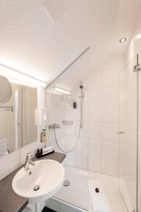 a white bathroom with a sink and a shower at Sorell Hotel Rex in Zurich