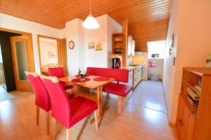 a kitchen and dining room with a wooden table and red chairs at Ferienwohnung Brunner - Haus am See in Nagel