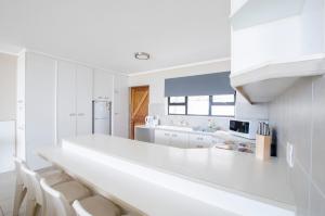 a white kitchen with white counters and white appliances at Herolds Bay Accommodation - Hiers Ons Weer Downstairs in Herolds Bay