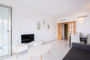 un salon blanc avec une table et une télévision dans l'établissement Apartamento Benidorm de Luxe, à Benidorm