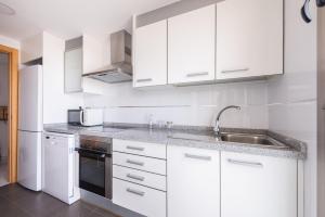 une cuisine blanche avec des armoires blanches et un évier dans l'établissement Apartamento Benidorm de Luxe, à Benidorm