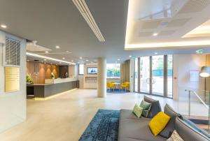 an office lobby with a couch and yellow pillows at Nemea Appart Hotel Cannes Palais in Cannes