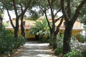 a yellow house with trees in front of it at PODERE OSLAVIA AZ.AGR.BIO GIANNINI in Alberese