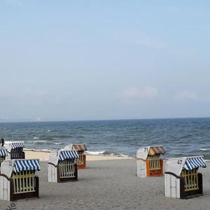 una fila de sillas de playa en una playa de arena en Ostseeabenteuer, en Scharbeutz