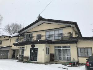 a house with a balcony on top of it in the snow at Hakuba West Coast Inn, Villa in Hakuba