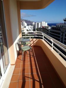 a balcony with two chairs and a table on it at Lido Funchal Apartment balcony sea view in Funchal