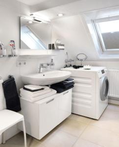 een witte badkamer met een wastafel en een wasmachine bij Ferienwohnung am Regierungsplatz in Landshut