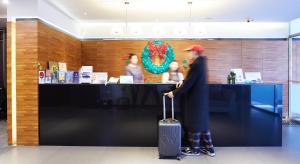 a man with a suitcase standing in front of a counter at Hai Fu Hotel & Suites in Jincheng