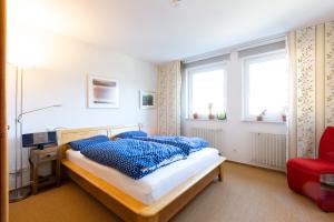 ein Schlafzimmer mit einem Bett mit blauen Kissen und einem roten Stuhl in der Unterkunft Deutsche Messe Zimmer - Private Apartments Hannover Exhibition Center (room agency) in Hannover