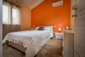 sypialnia z białym łóżkiem i pomarańczową ścianą w obiekcie Villa Gea w mieście Castellammare del Golfo +19 zdjęć