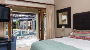 a bedroom with a bed and a television and a patio at Manor 38 in Port Elizabeth +57 photos