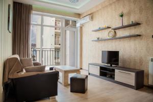 sala de estar con TV, sofá y silla en TB Apart-Hotel in Tbilisi 1 en Tiflis