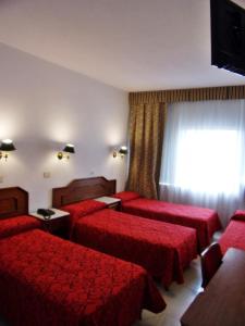 una camera d'albergo con tre letti e una televisione di Hotel Tres Sargentos a Buenos Aires
