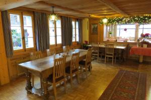 Guggisberg的住宿－Hotel Restaurant Sternen，用餐室设有木桌、椅子和窗户。
