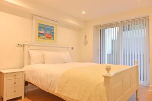 een witte slaapkamer met een bed en een raam bij The Sanctuary in Eastbourne