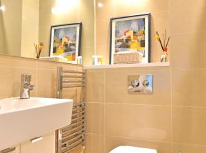 een badkamer met een wastafel, een toilet en een spiegel bij The Sanctuary in Eastbourne
