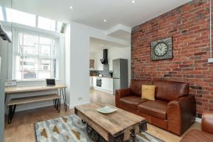 een woonkamer met een bank en een bakstenen muur bij Park House - Large 3 Bedroom Victorian House, 10 Mins from Manchester in Manchester