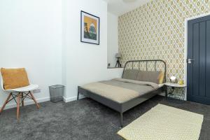 een slaapkamer met een bed en een stoel bij Park House - Large 3 Bedroom Victorian House, 10 Mins from Manchester in Manchester