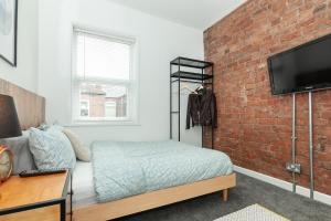 een slaapkamer met een bed en een bakstenen muur bij Park House - Large 3 Bedroom Victorian House, 10 Mins from Manchester in Manchester