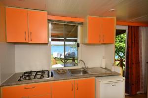 une cuisine avec des armoires orange et un évier ainsi qu'une fenêtre dans l'établissement Arena Tasalera Mobile Homes, à Premantura