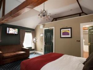 1 dormitorio con cama, sofá y TV en The Hatchet Inn Wetherspoon en Newbury