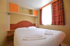 um quarto com uma cama branca com duas toalhas em Arena Tasalera Mobile Homes em Premantura