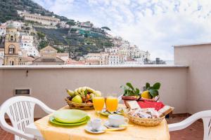 uma mesa com fruta e sumo numa varanda com vista em Casa dei Greci em Amalfi