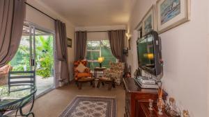 Una sala de estar con televisión, mesa y sillas. en Brown Jug Guest House, en Hermanus