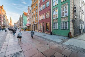 a group of people walking down a street with buildings at Golden Gate by Loft Apartments in Gdańsk