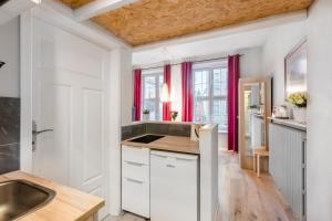 a kitchen with white cabinets and red curtains at Golden Gate by Loft Apartments in Gdańsk