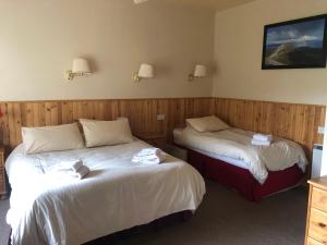 two beds in a room with wood paneling at Port Askaig Hotel in Port Askaig