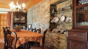 a dining room with a table and a stone wall at Casa dos Araújos in Frechas