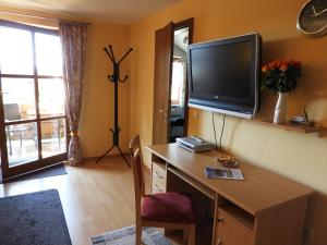 Habitación con escritorio y TV en la pared. en Appartements Hirsch en Bad Birnbach