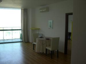 ein Esszimmer mit einem Tisch, Stühlen und einem Fenster in der Unterkunft Sea view, 2 room apartment 703, Primorsko in Primorsko