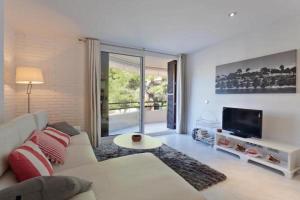 a living room with a white couch and a tv at Apartment near the Pine Walk in Pollença