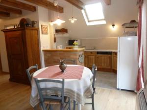 a kitchen with a table and a white refrigerator at L'Alcôve des p'tits coeurs in Benfeld