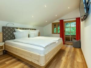 Un dormitorio con una gran cama blanca con cortinas rojas. en Ferienwohnung Staffen, en Unterwossen