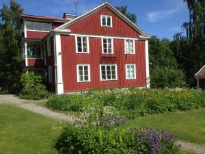 uma casa vermelha e branca com jardim e flores em Tvetagårdens Vandrarhem em Södertälje